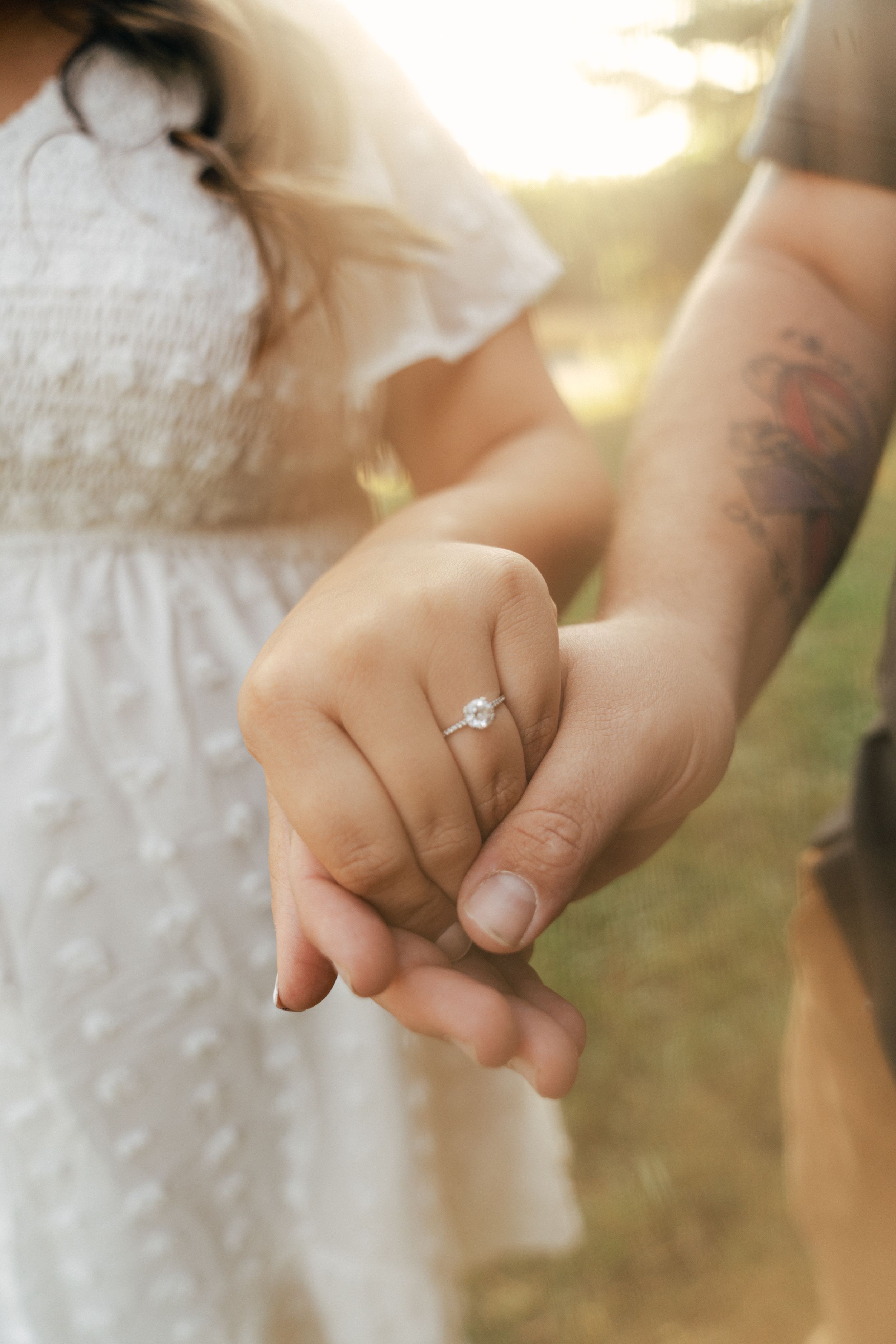 Close-up shot of hands displaying an engagement ring in soft natural lighting.