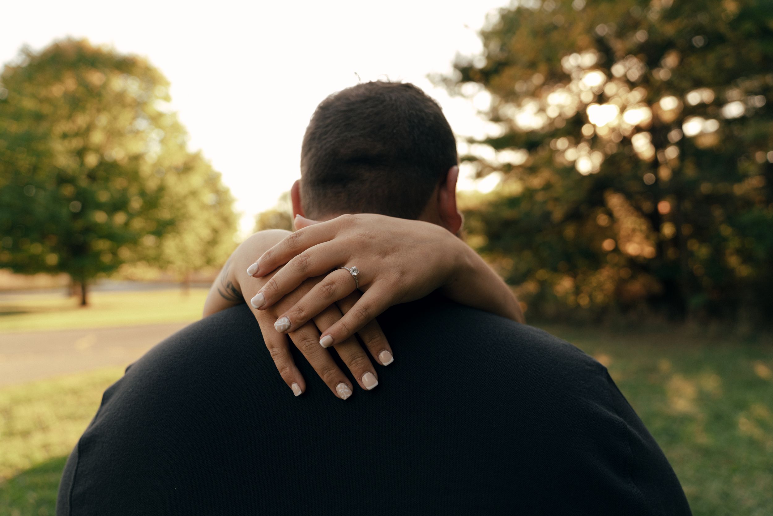 Intimate close-up of hands resting on shoulders during a romantic moment.