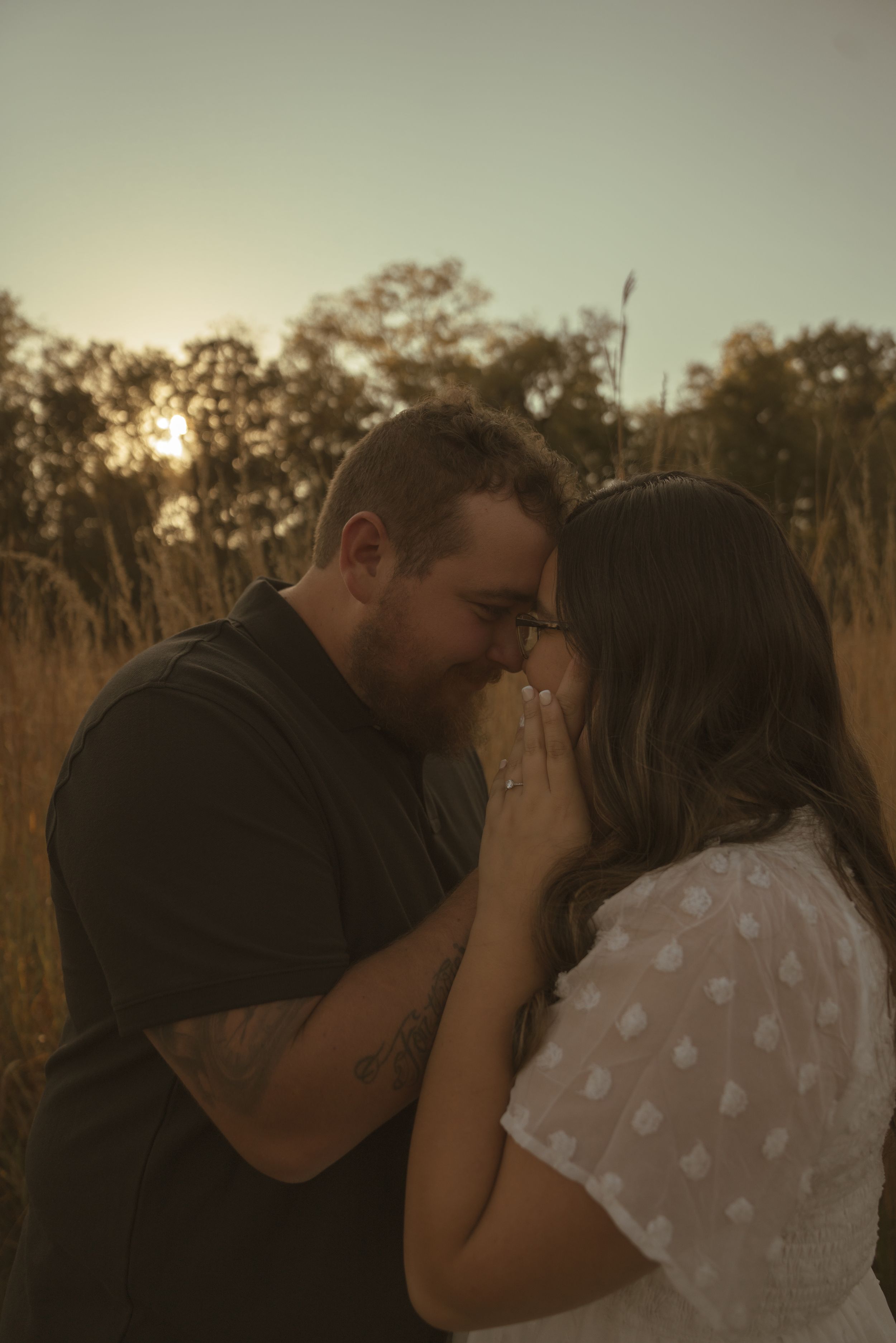 A tender moment between a couple in a field during golden hour.