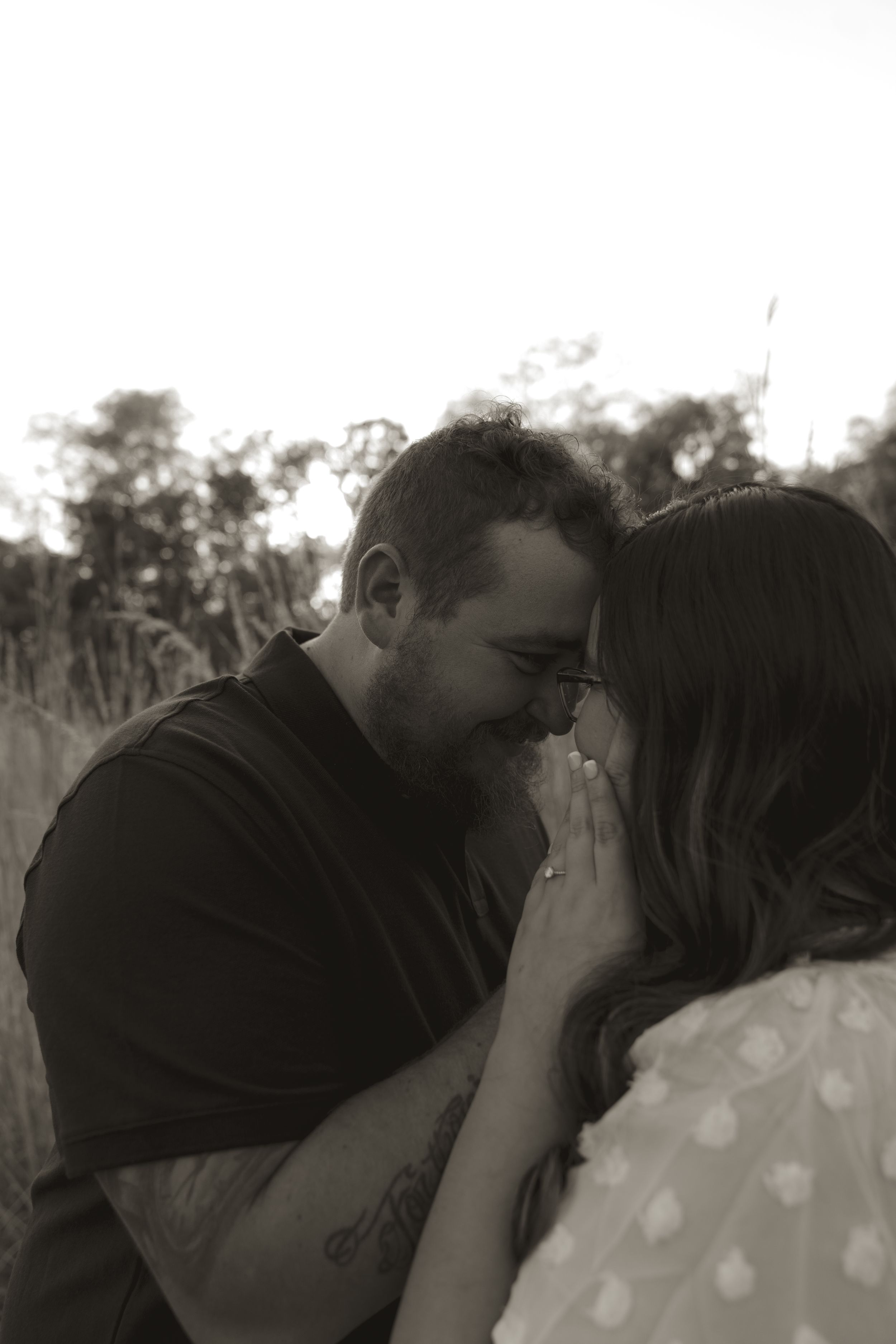 An intimate black and white portrait of a couple embracing in nature.