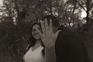 A joyful couple showing their hands to the camera in an outdoor setting.