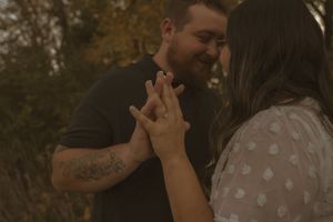 A couple sharing a romantic moment among tall grass at sunset.