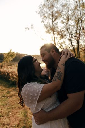 Intimate couple's portrait with dramatic sunset lighting in a natural outdoor setting.
