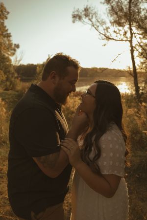 Romantic sunset portrait with couple embracing among trees.