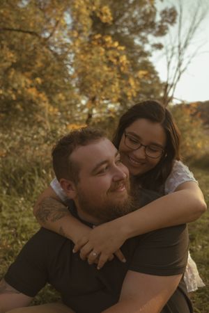 Playful couple sharing joyful moment outdoors during autumn photo session.