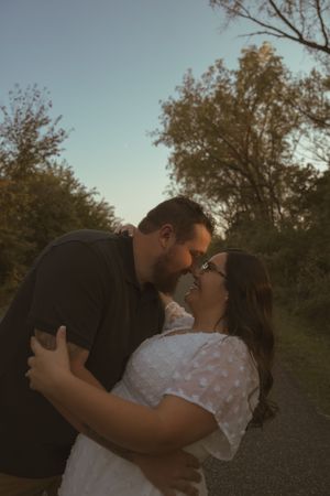 Romantic couple embracing in outdoor setting with autumn trees and blue sky.