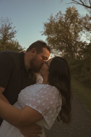 Intimate moment between couple during sunset photoshoot on nature trail.