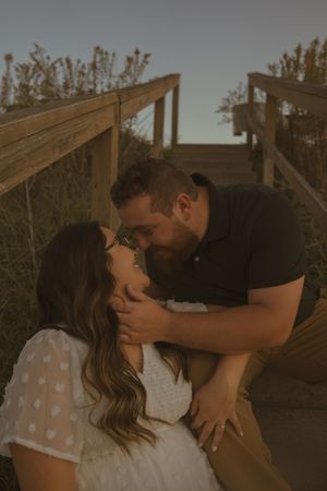 An intimate moment captured between two people on a rustic wooden structure.
