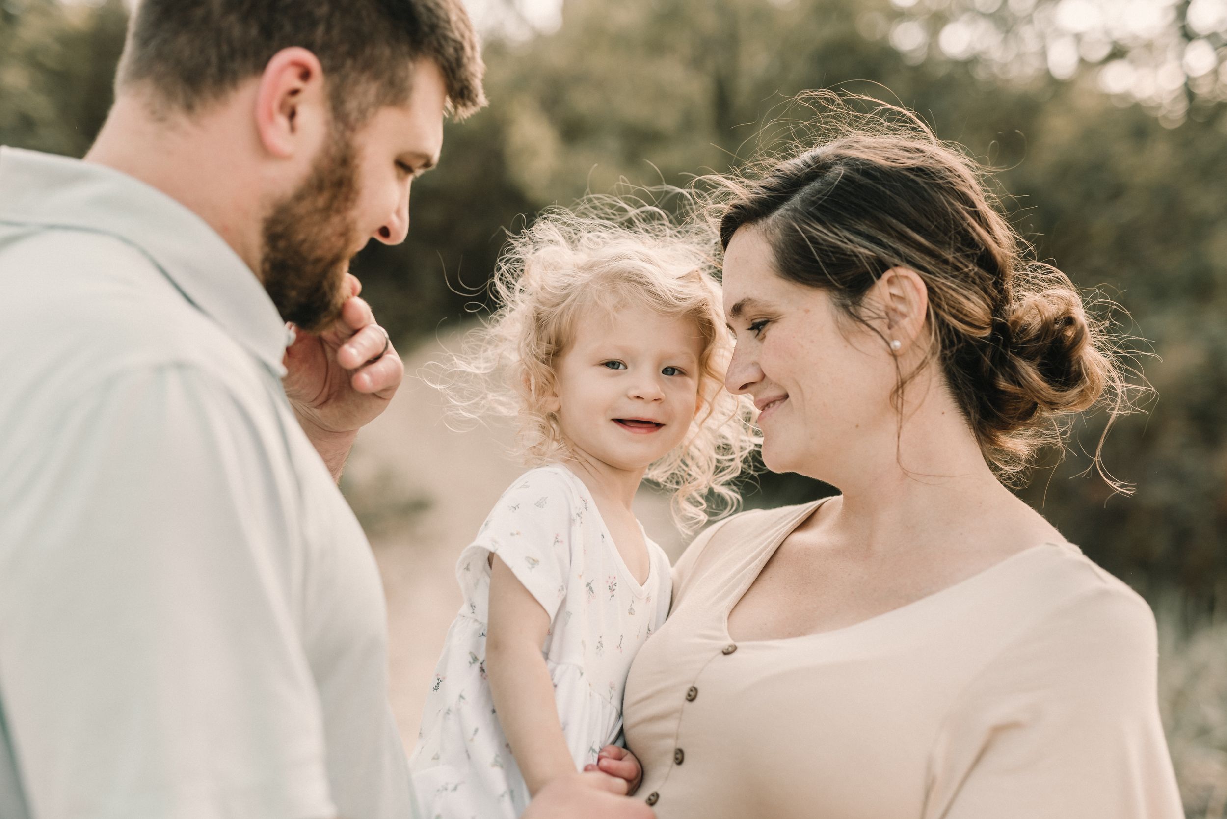 A family shares an intimate moment together during an outdoor maternity portrait session.