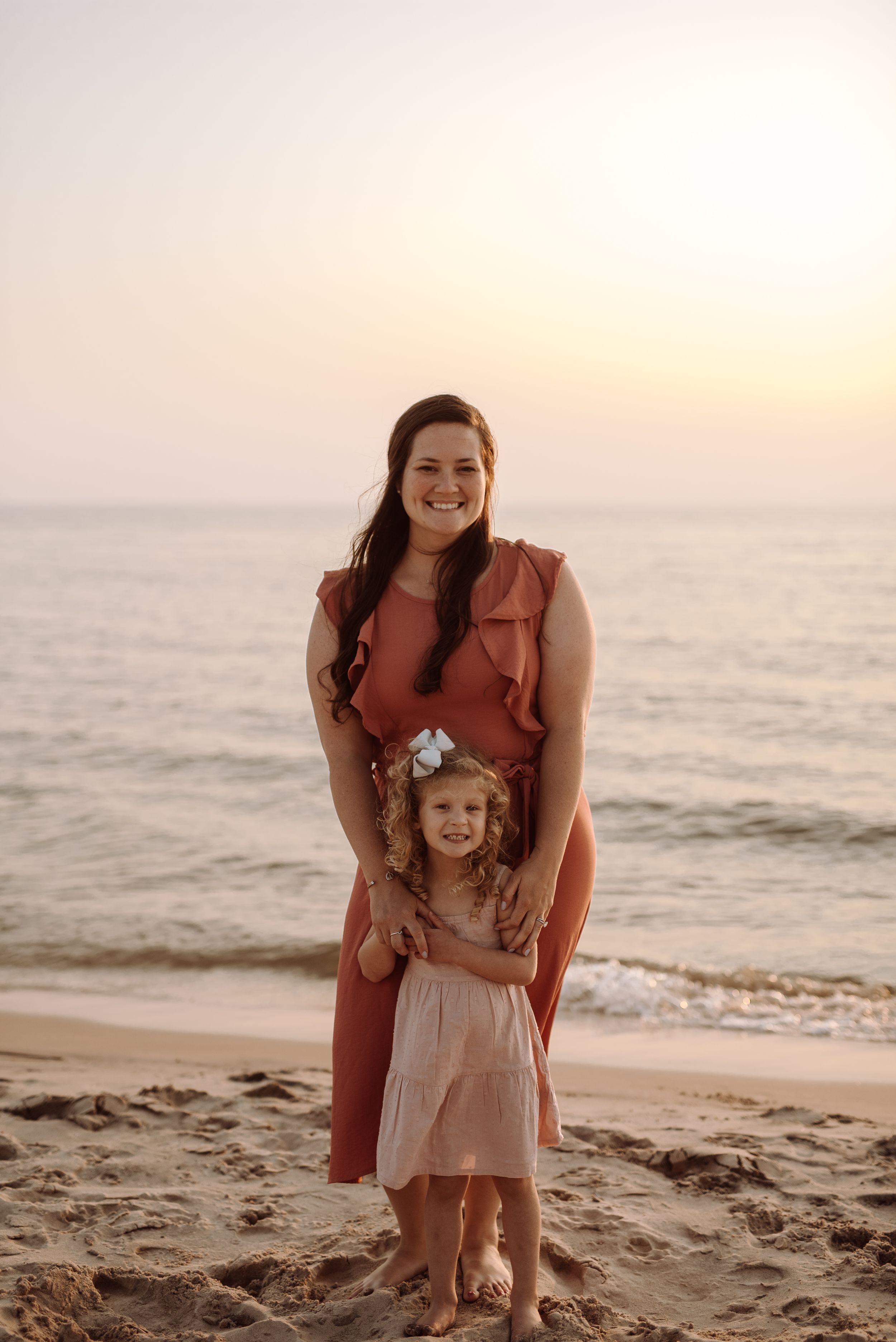 A parent and child enjoying a playful moment together on a beach during golden hour.