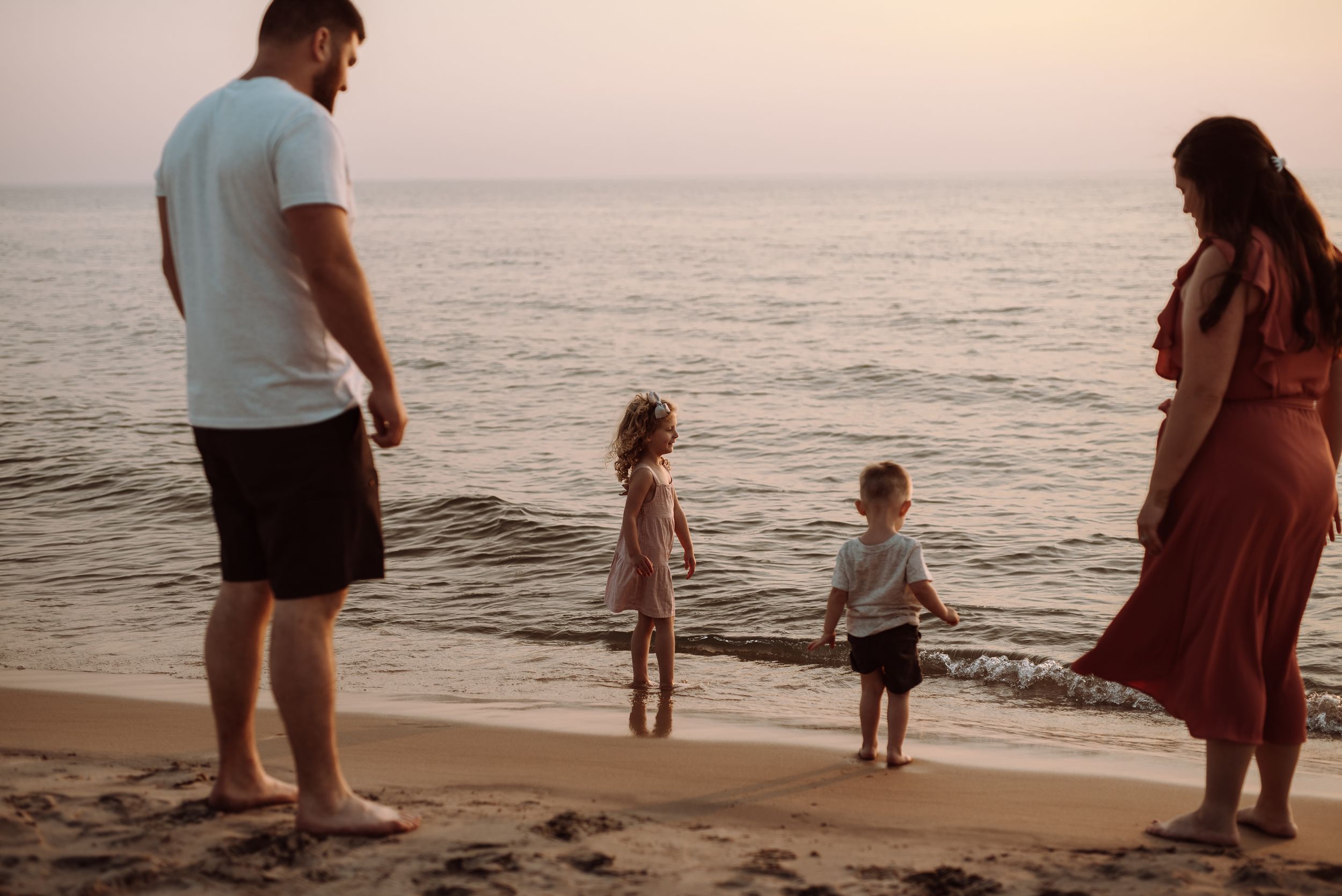 Family spending time together watching sunset on a peaceful beach.