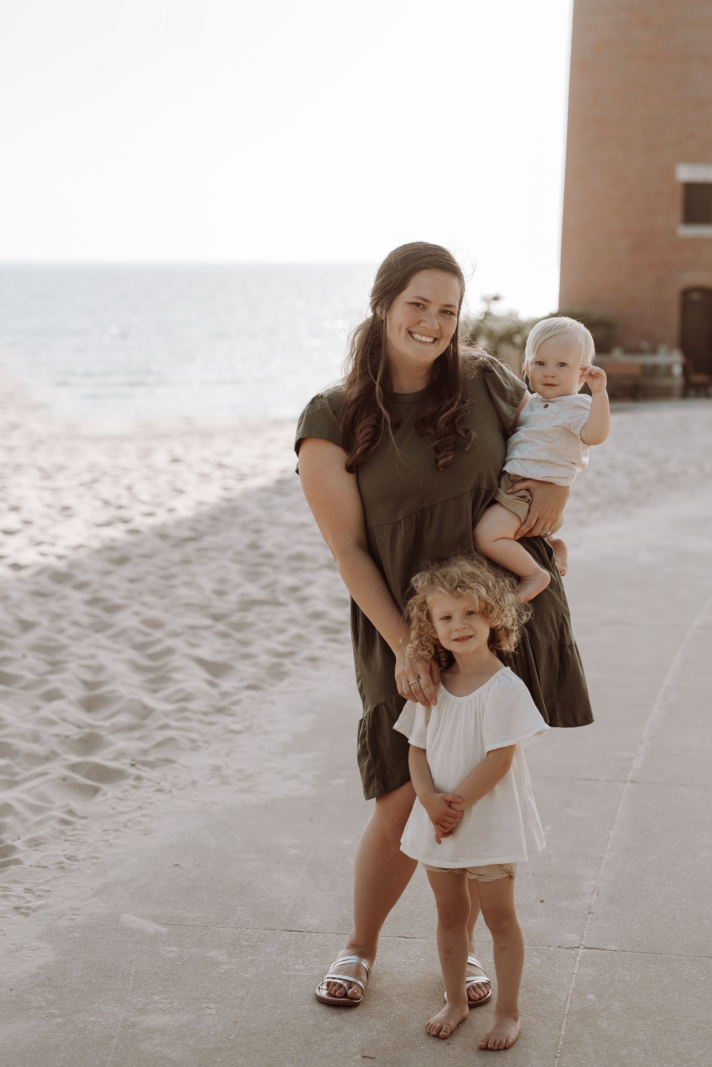 Family enjoying a sunset moment together on a sandy beach path with warm natural lighting.