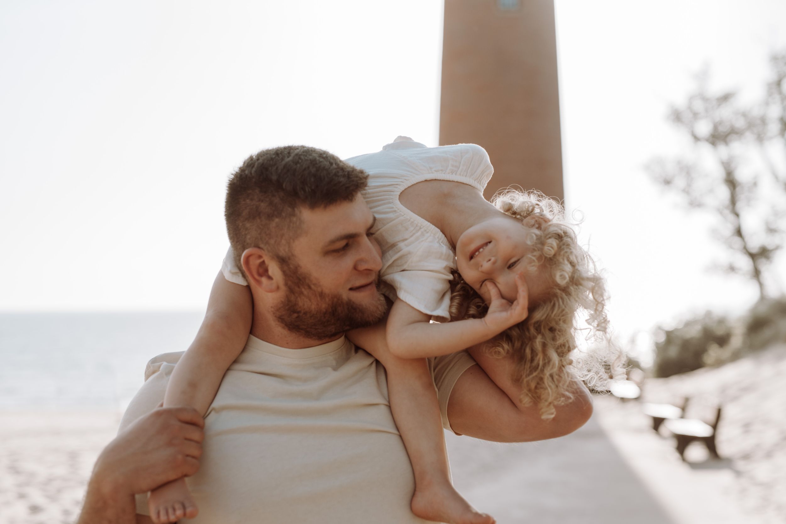 A couple dressed in beige and white shares tender moments together in a desert landscape during a romantic photoshoot.