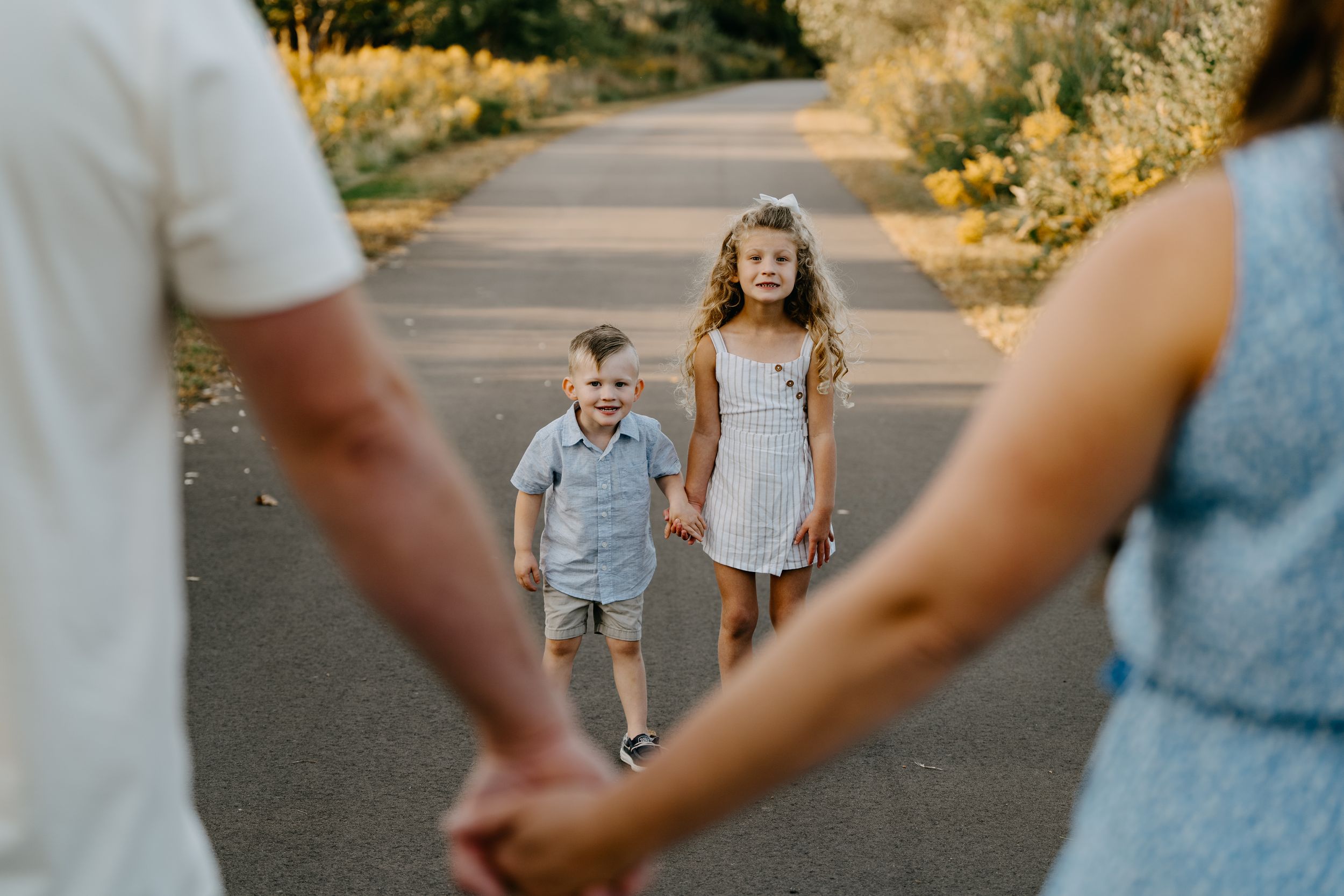 Children walking on a path between two adults holding hands at sunset on a warm summer evening.