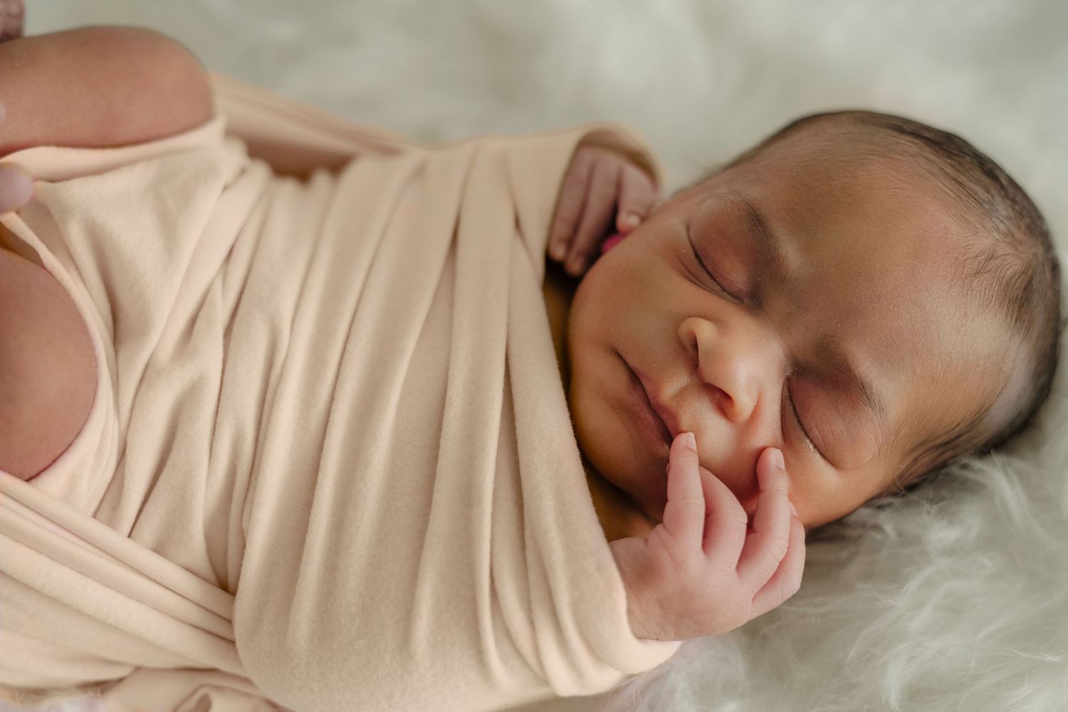 Black newborn baby swaddled in blanket