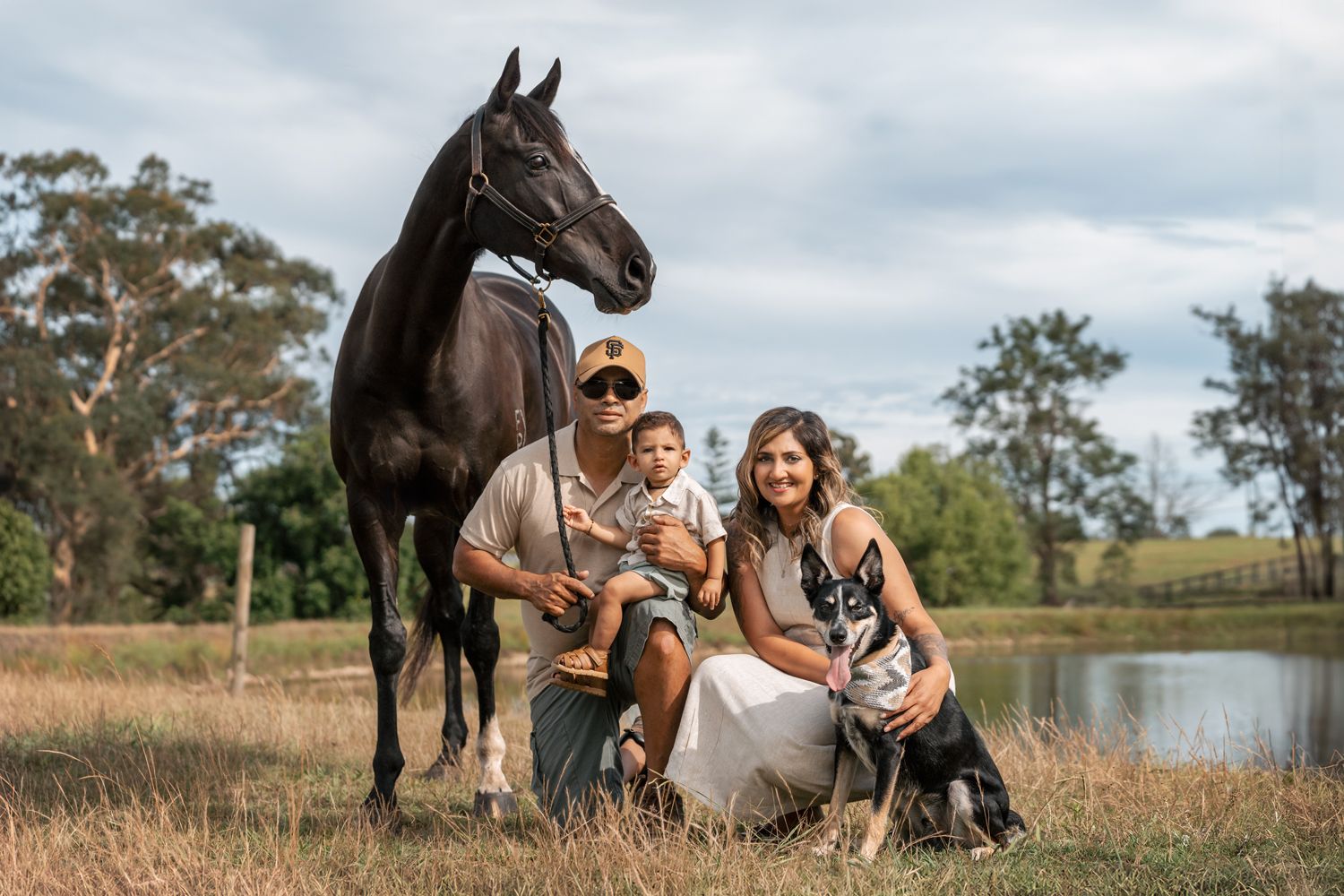 family photographer in sydney near me is taking a photo of a family with a toddler and their dog and horse in Cattai