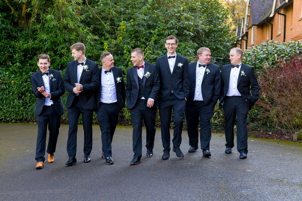 Groom and groomsmen walking and laughing in tuxedos