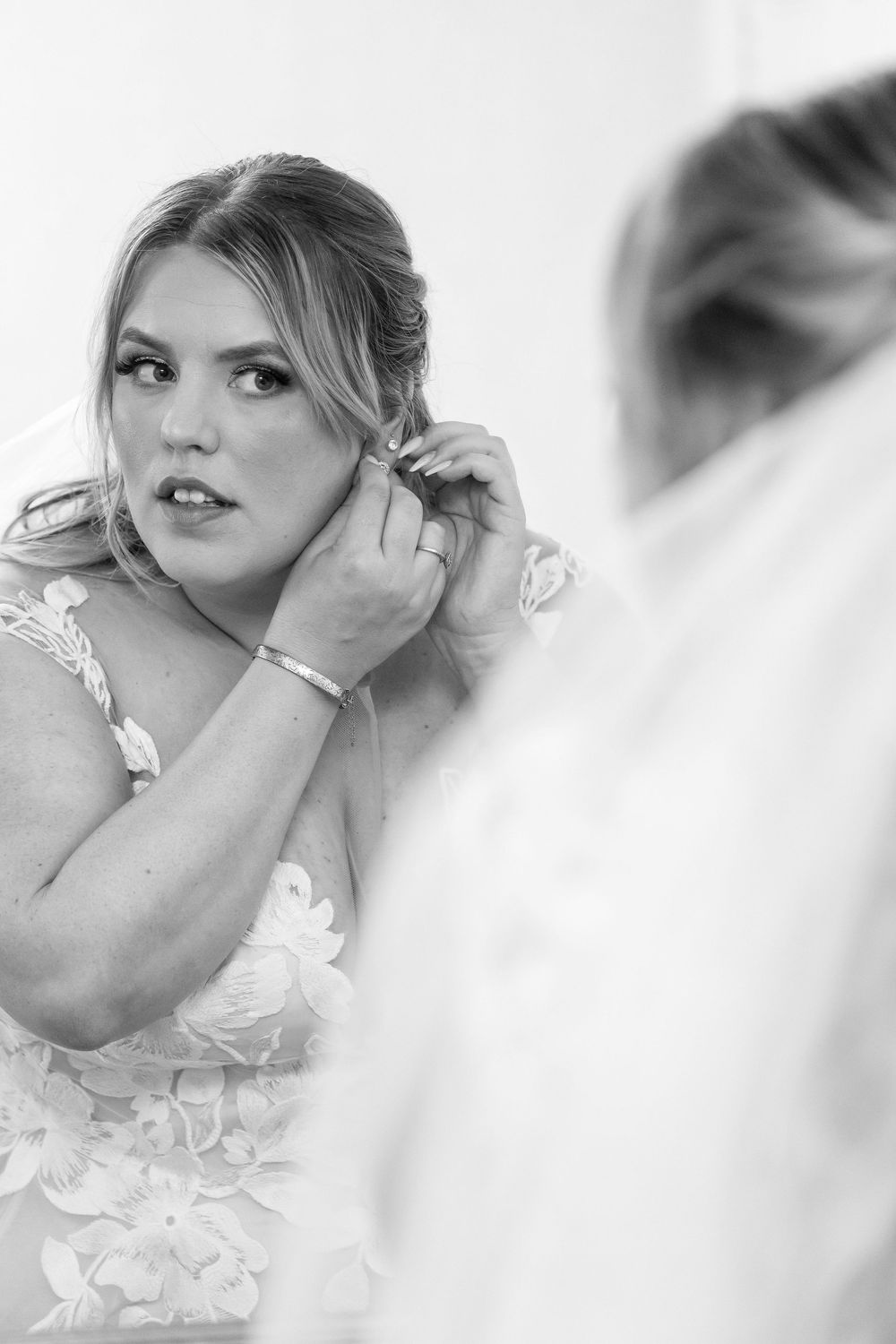 Bride putting on earrings in front of a mirror