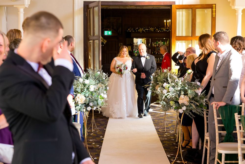 Bride walking down the aisle with her father as guests look on at Audleys Wood Hotel