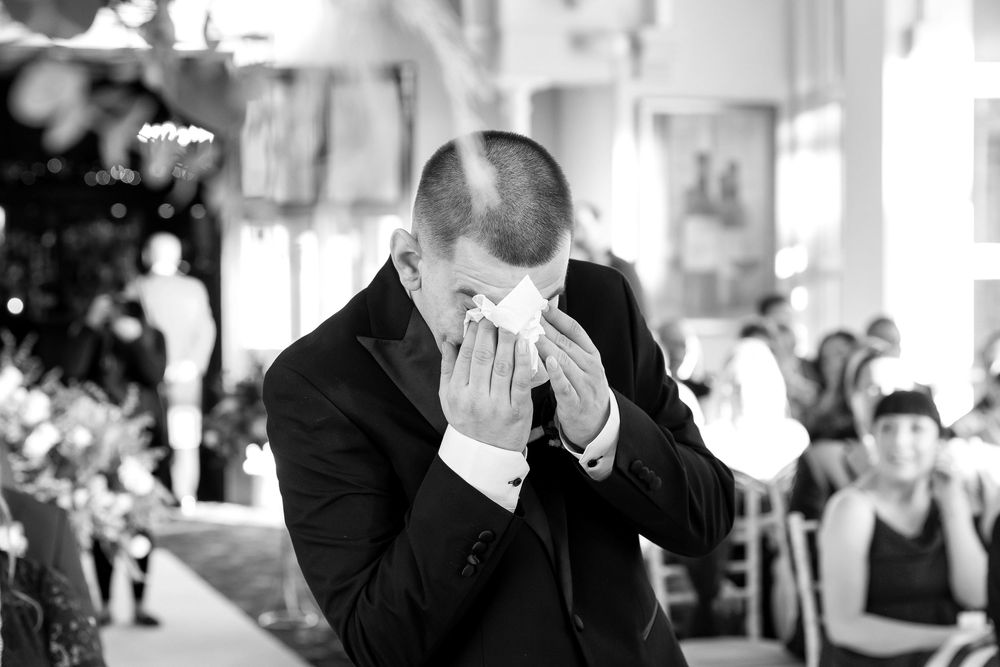 Groom wiping tears during emotional wedding ceremony
