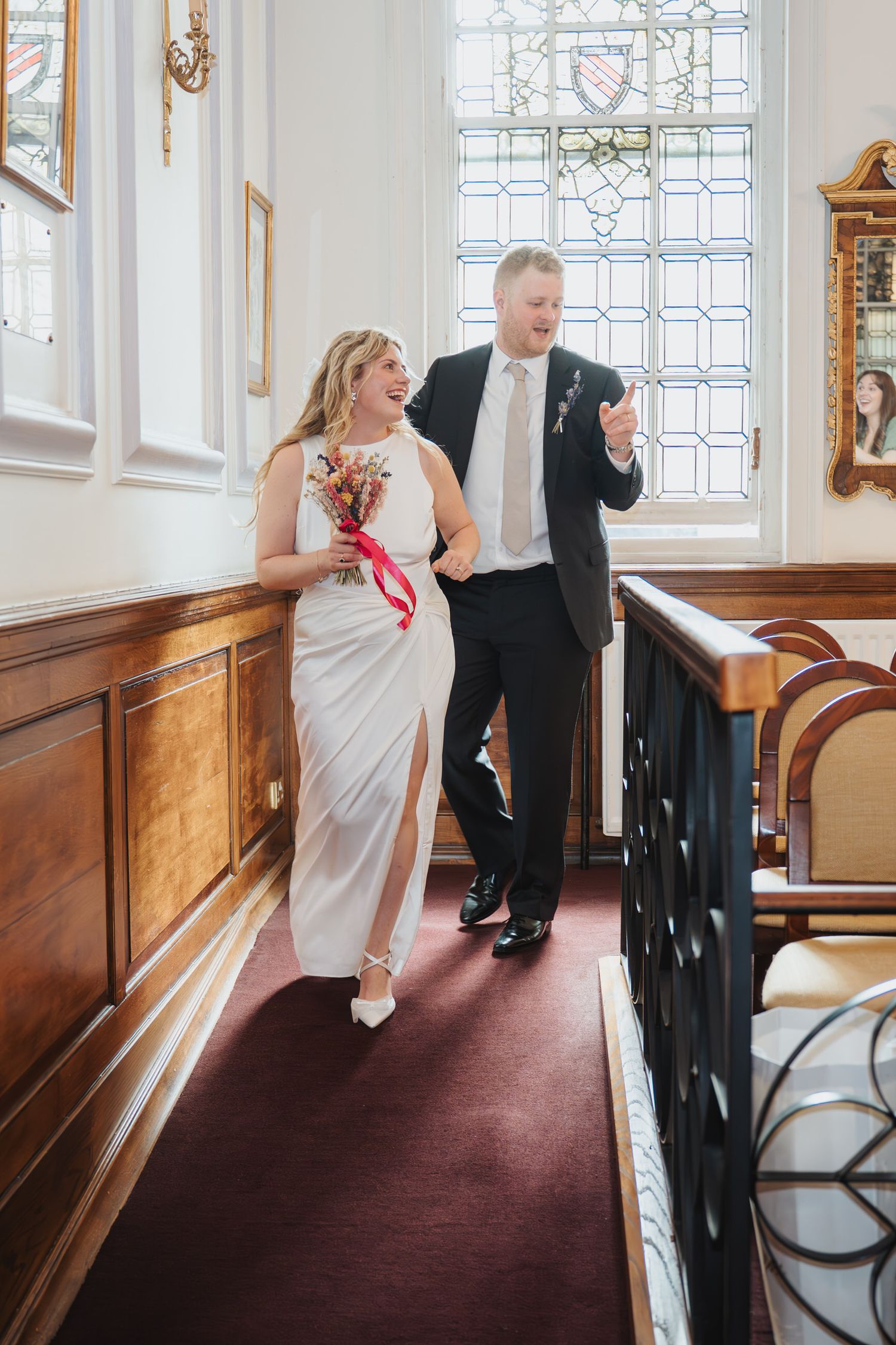 Newlywed couple walk joyfully down the aisle holding a colourful bouquet after their wedding ceremony at Oxford Registry Office