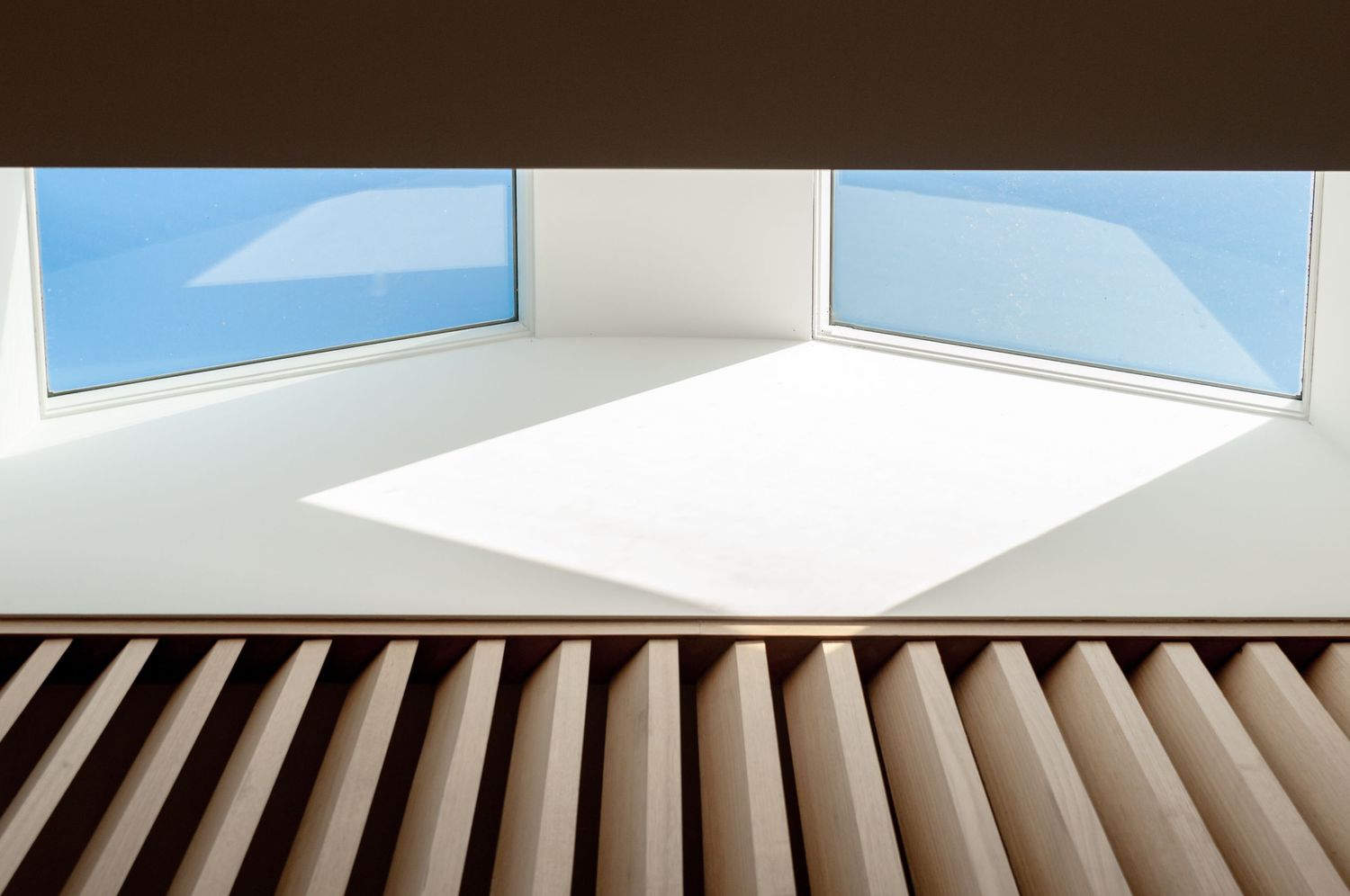 Modern architectural detail showing wooden slats below corner windows with bright natural light entering the space.
