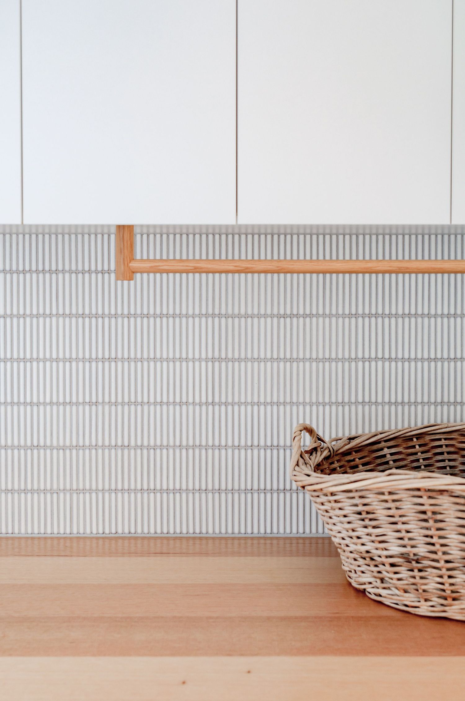 White kitchen cabinets with vertical tile backsplash and wooden shelving detail.