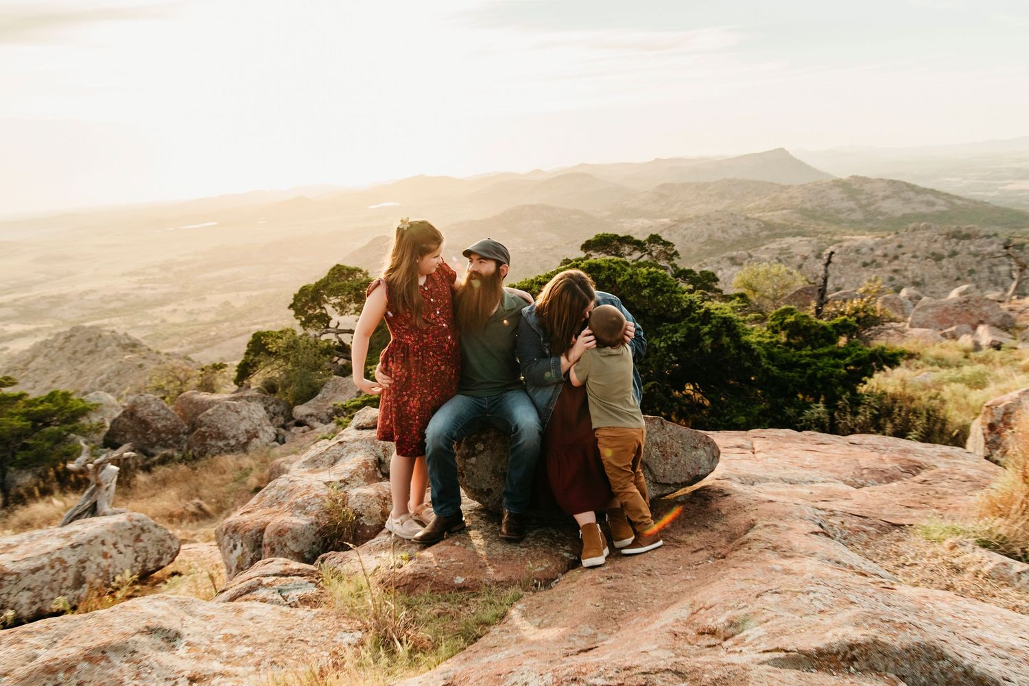 Group gathered on rocky mountain overlook during golden hour with scenic desert vista.