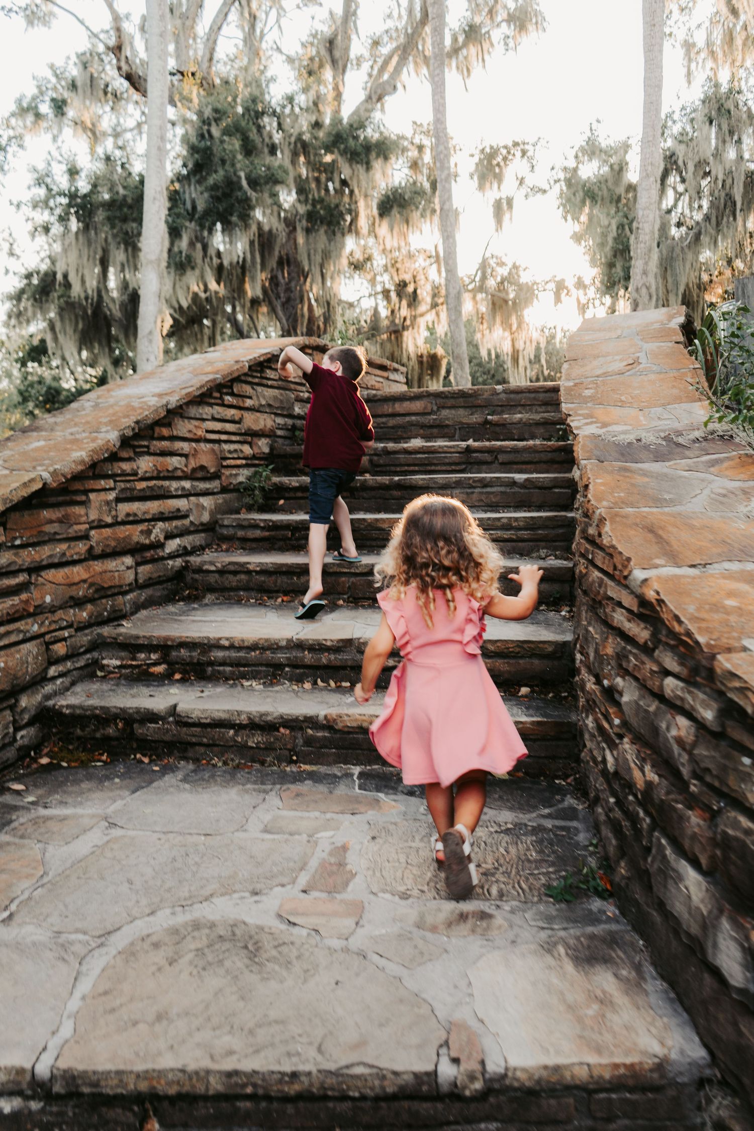 Outdoor Family Session Philippe Park in Safety Harbor, FL; young boy and girl running up stone stairs at sunset