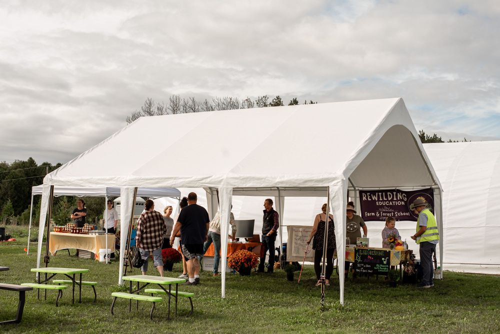 Large white event tent set up on grass with vendors and visitors inside.