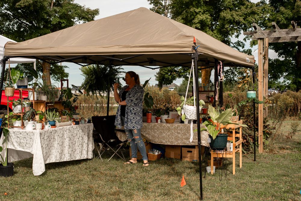 Pop-up vendor tent with tables displaying merchandise at an outdoor market or craft fair.