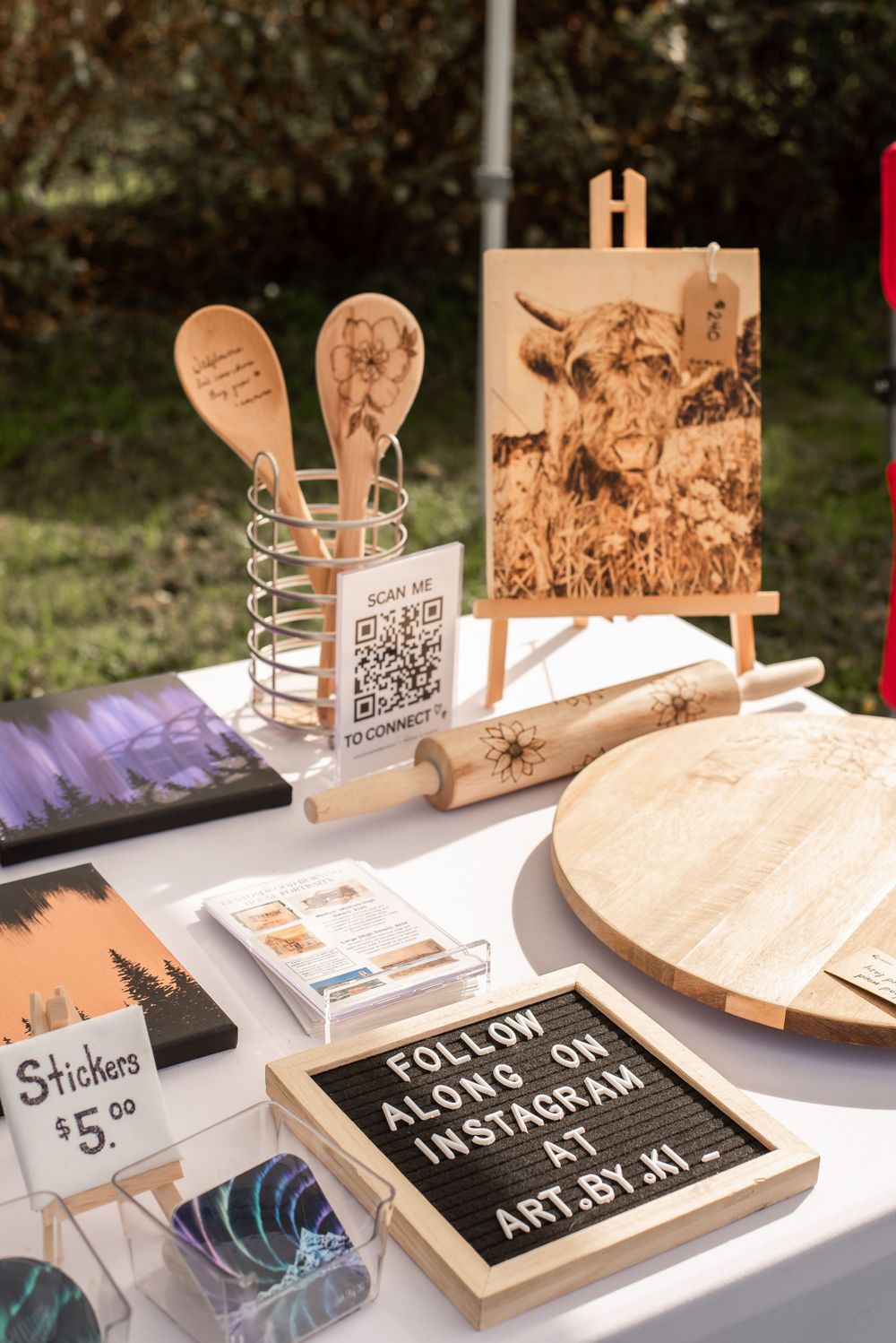 Wooden crafts and merchandise display with QR code and letterboard signage.