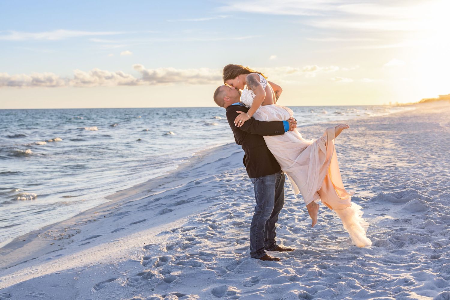 A romantic beach embrace during sunset with the ocean waves in the background.