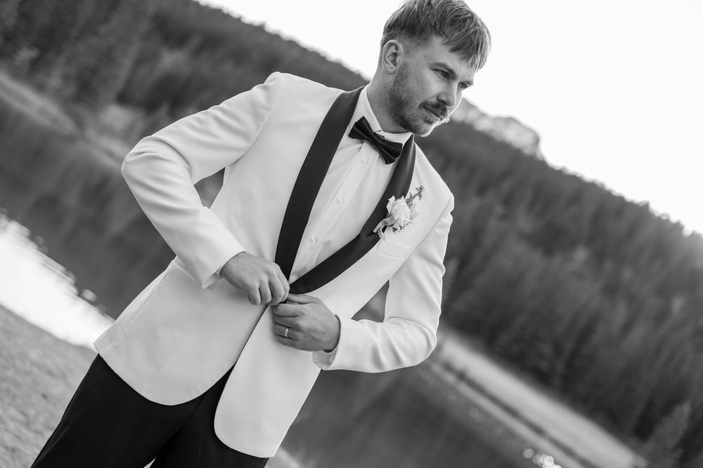 Black and white wedding photos show a couple celebrating outdoors in formal attire with white jackets and ties.