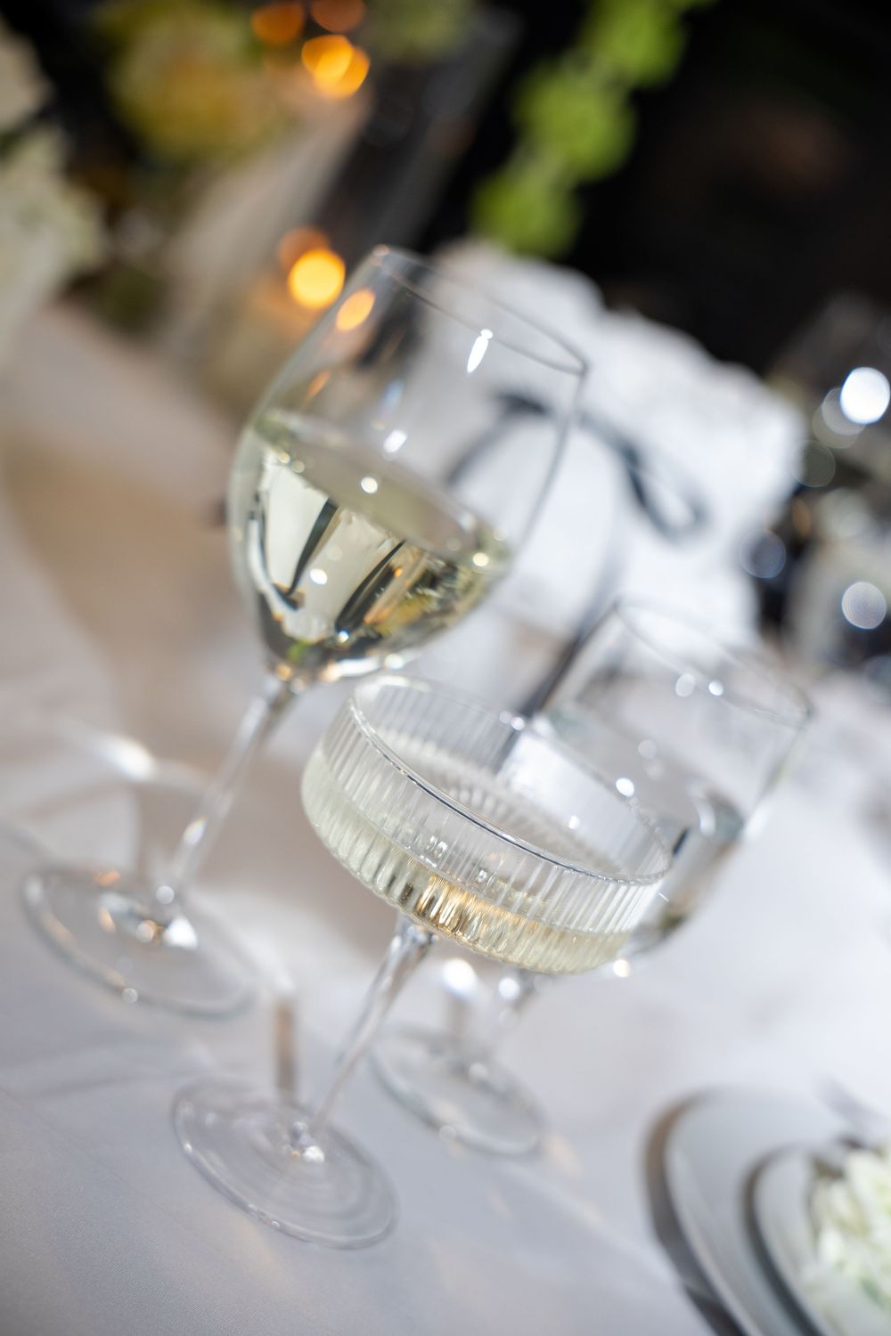 Wine glasses arranged on an elegant white tablecloth with soft bokeh lighting in the background create an upscale dining ambiance.