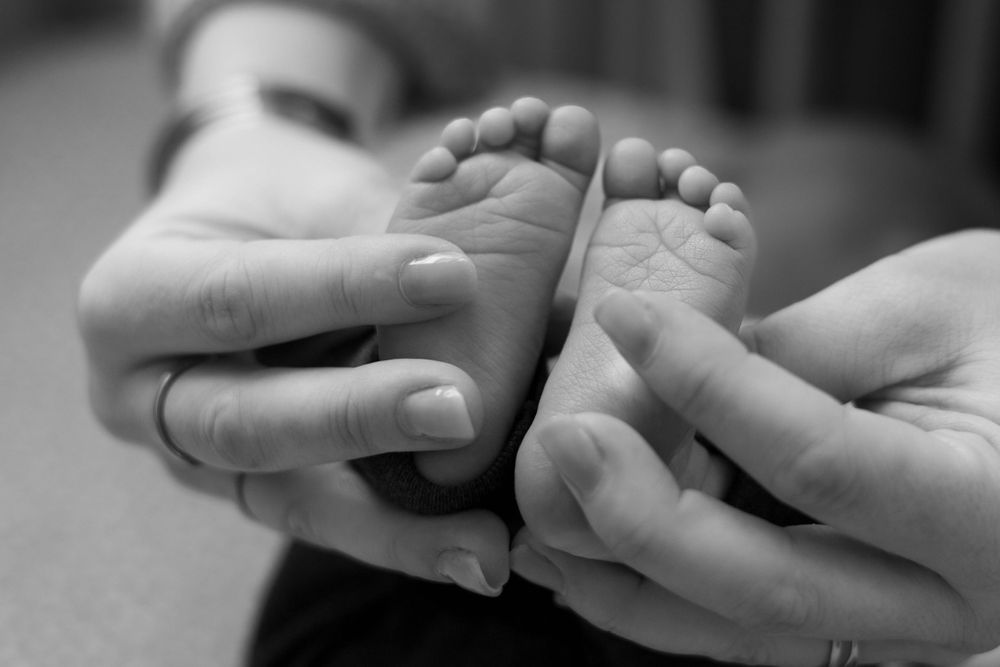 Gently hold tiny baby feet in black and white.