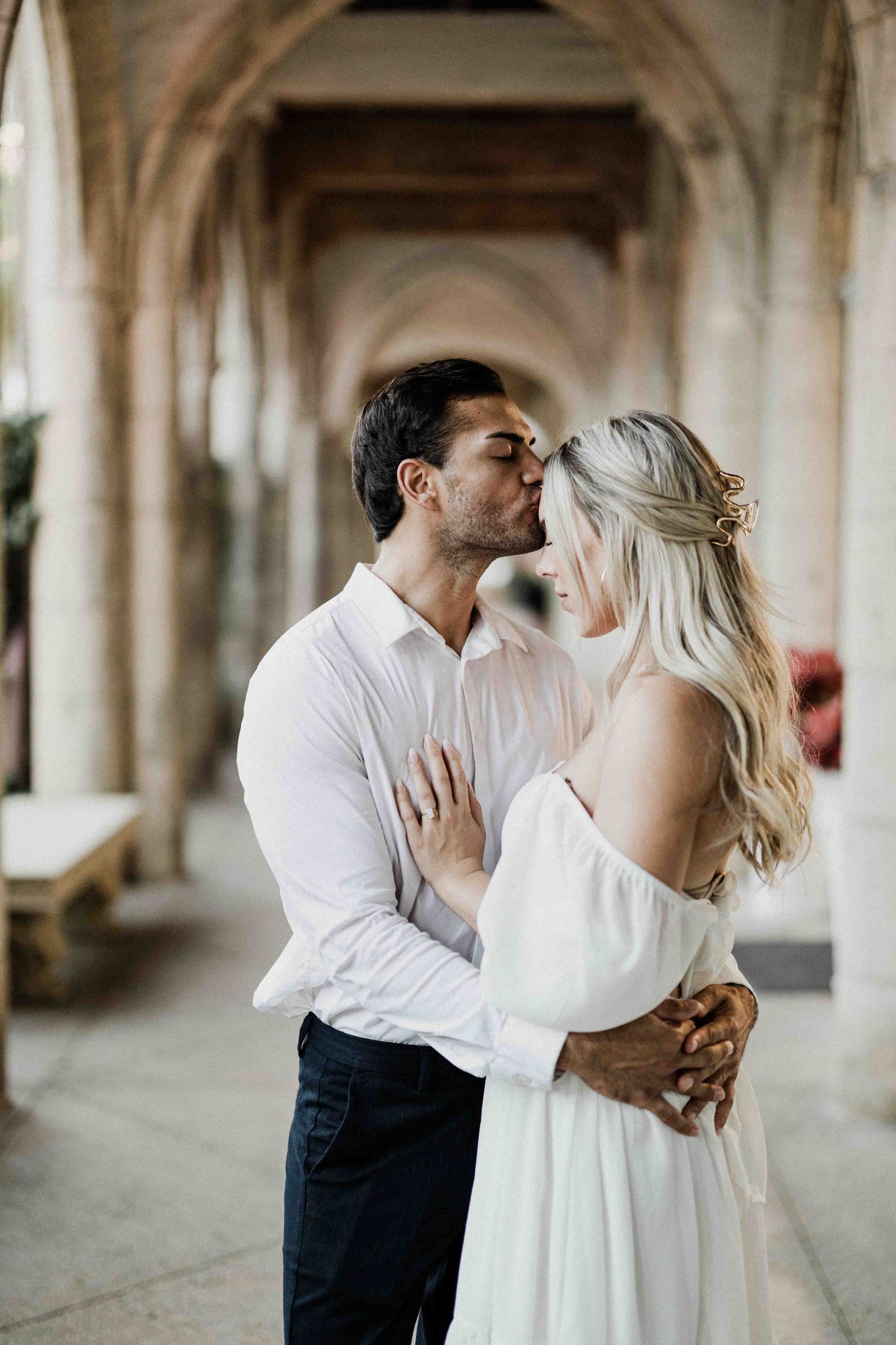 Romantic couple sharing a tender moment in an elegant arched corridor.