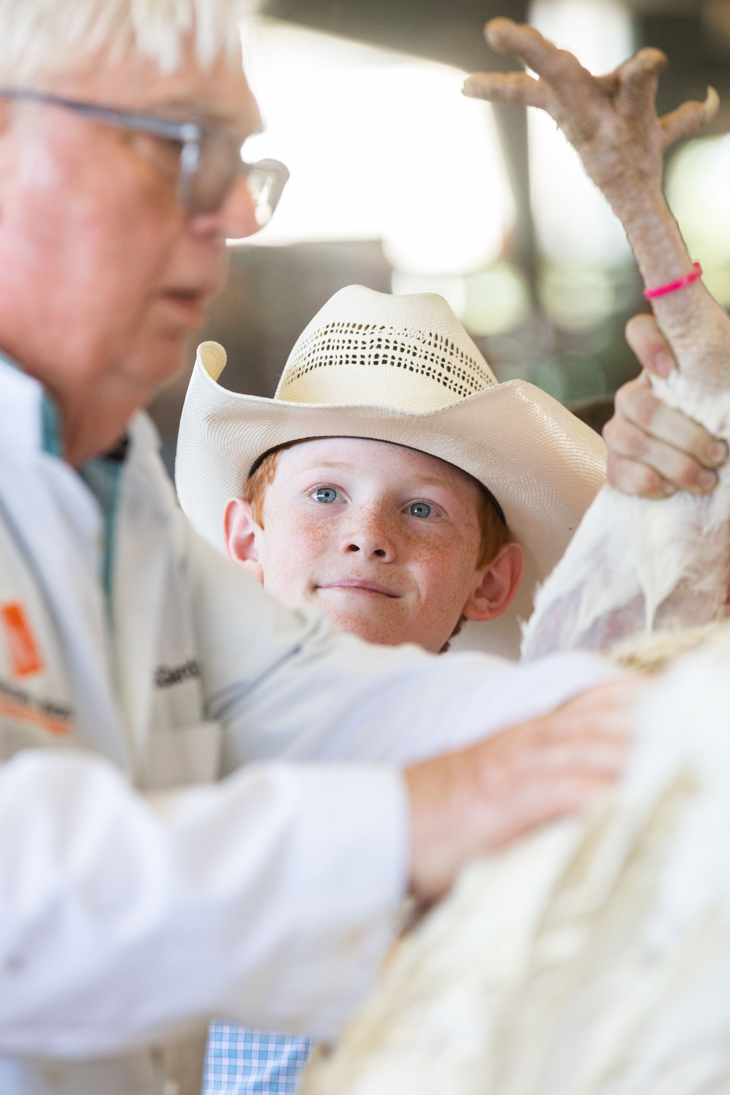 Children in white clothing and straw hats participate in an outdoor event.