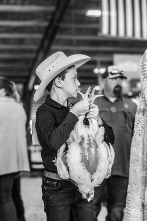 Young handlers wearing cowboy hats present their sheep at a western livestock show.