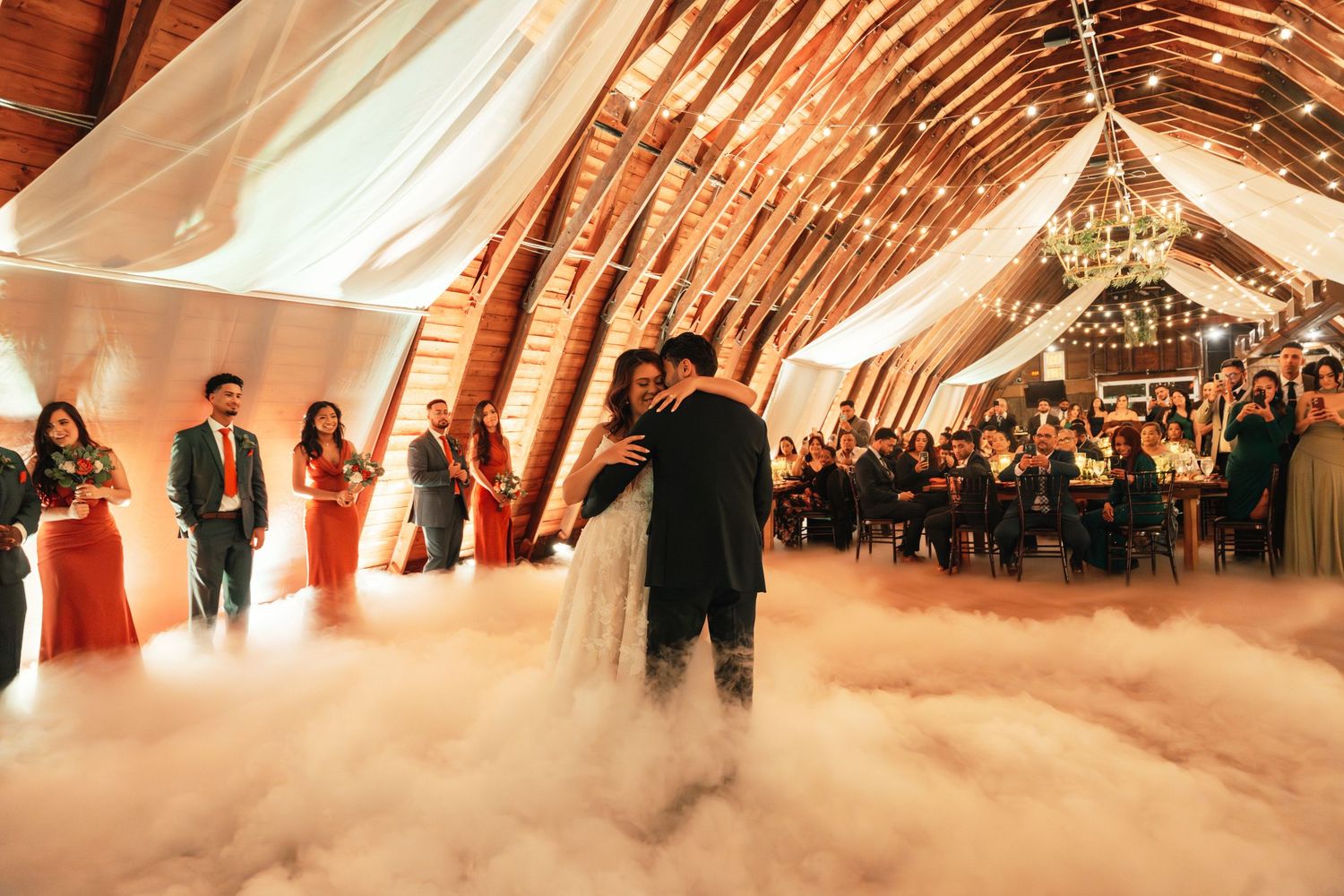 Wedding reception in a rustic barn with dramatic lighting and elegant decor.