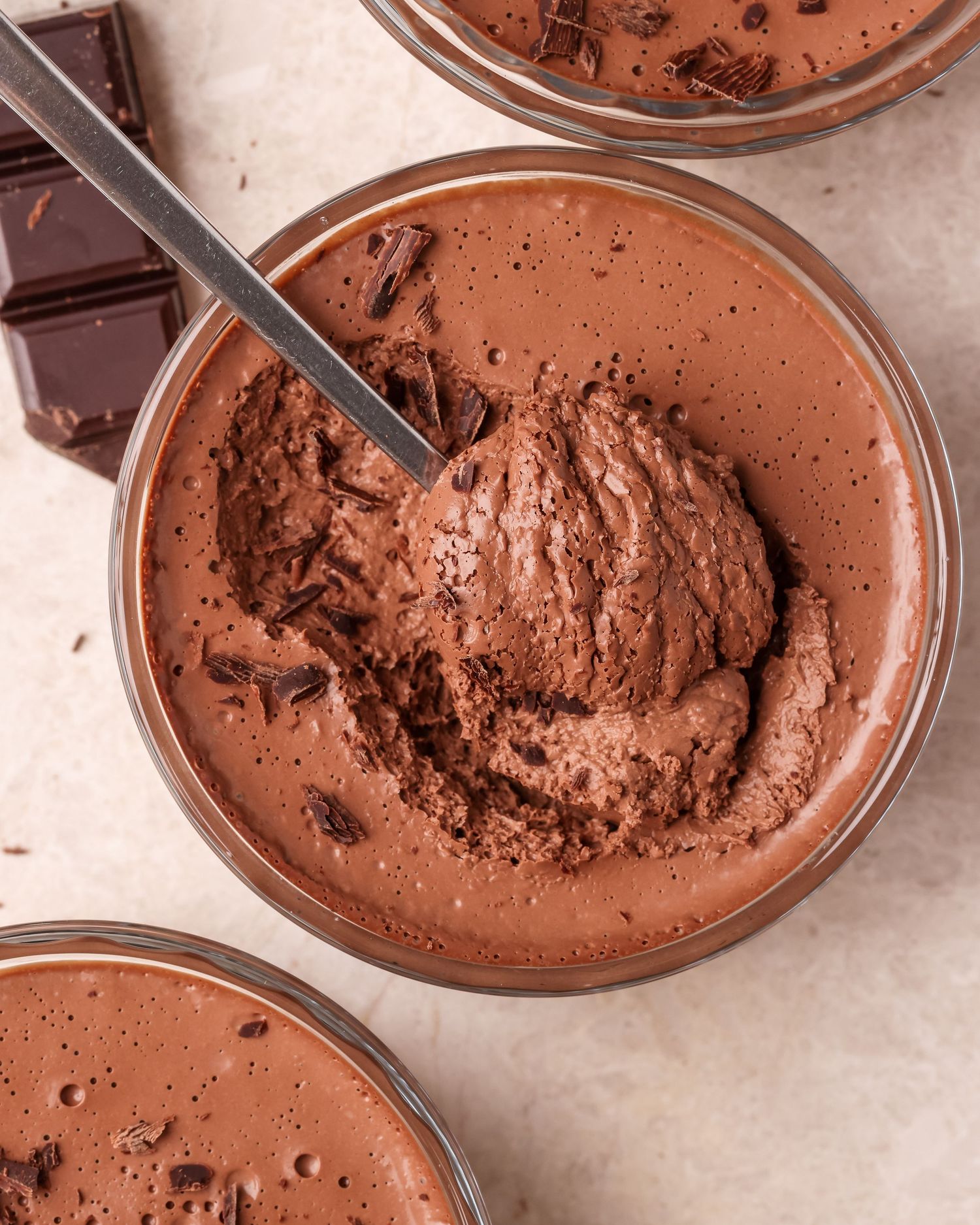 Close-up of chocolate mousse desserts in glass bowls with smooth and textured surfaces.