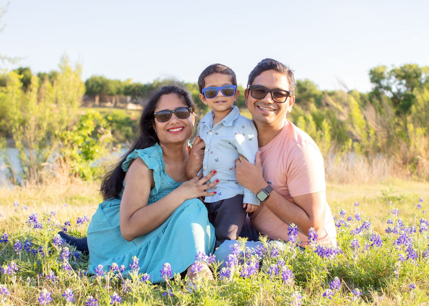 bluebonnet mini session cedar park texas family sits in bluebonnets with sunglasses for a spring mini session with bluebonnets