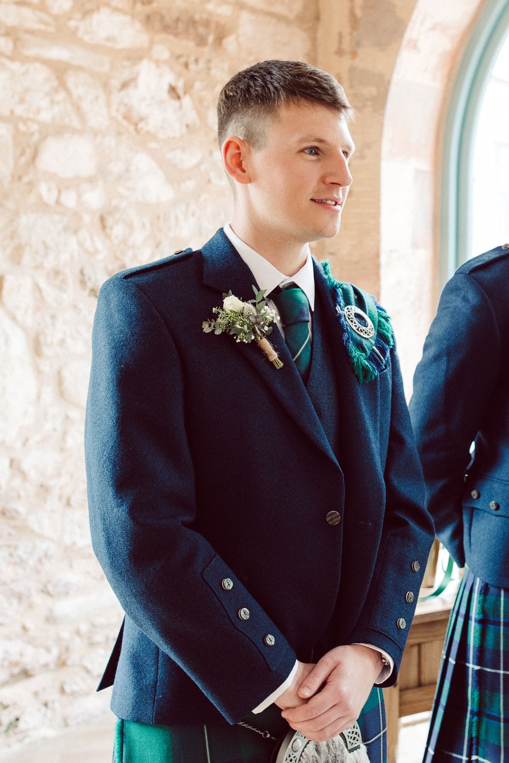 Three people in formal black jackets and Scottish tartan kilts stand together during a traditional ceremony.