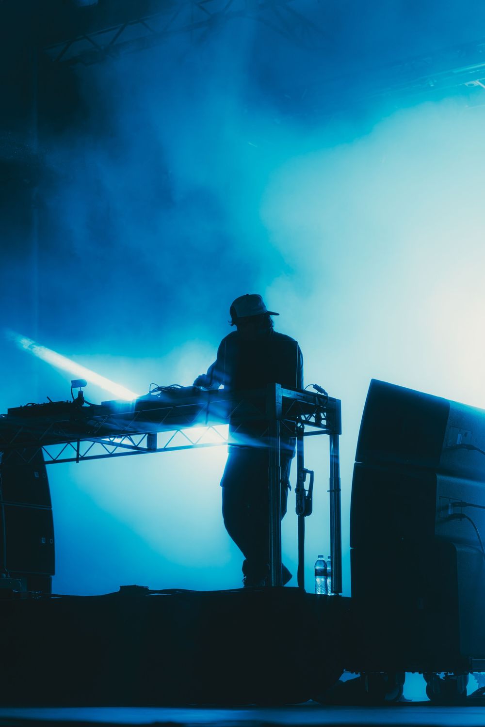 Silhouettes of musicians performing on stage against a dramatic blue backlit background during a concert performance.