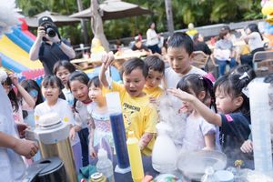Children participate in an outdoor science experiment with cups and water on a sunny day in a school setting.在陽光明媚的日子裡，孩子們在學校參加一項戶外科學實驗