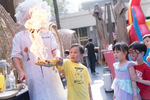 A science demonstration with fire captivates a group of excited children at an outdoor educational event.在戶外教育活動中，一場與火有關的科學演示吸引了一群興奮的孩子們的目光。