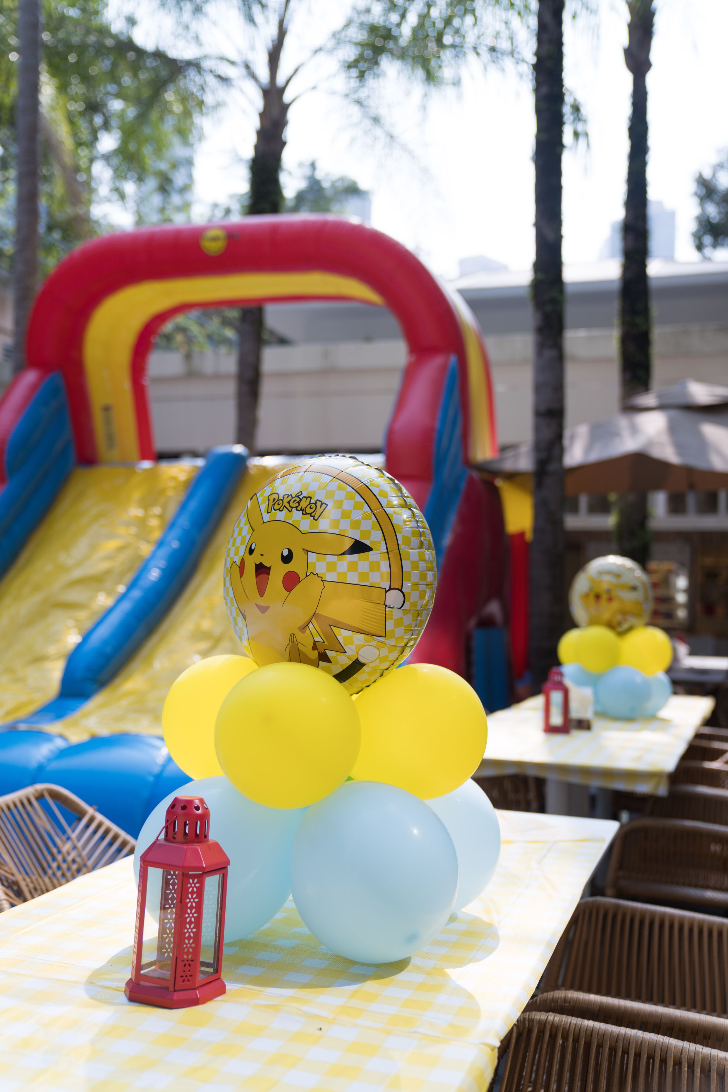 Yellow and blue inflatable bounce house with party decorations and balloons set up at an outdoor event venue.戶外活動場地內搭建了一個黃藍相間的充氣彈跳床，並裝飾有派對飾品