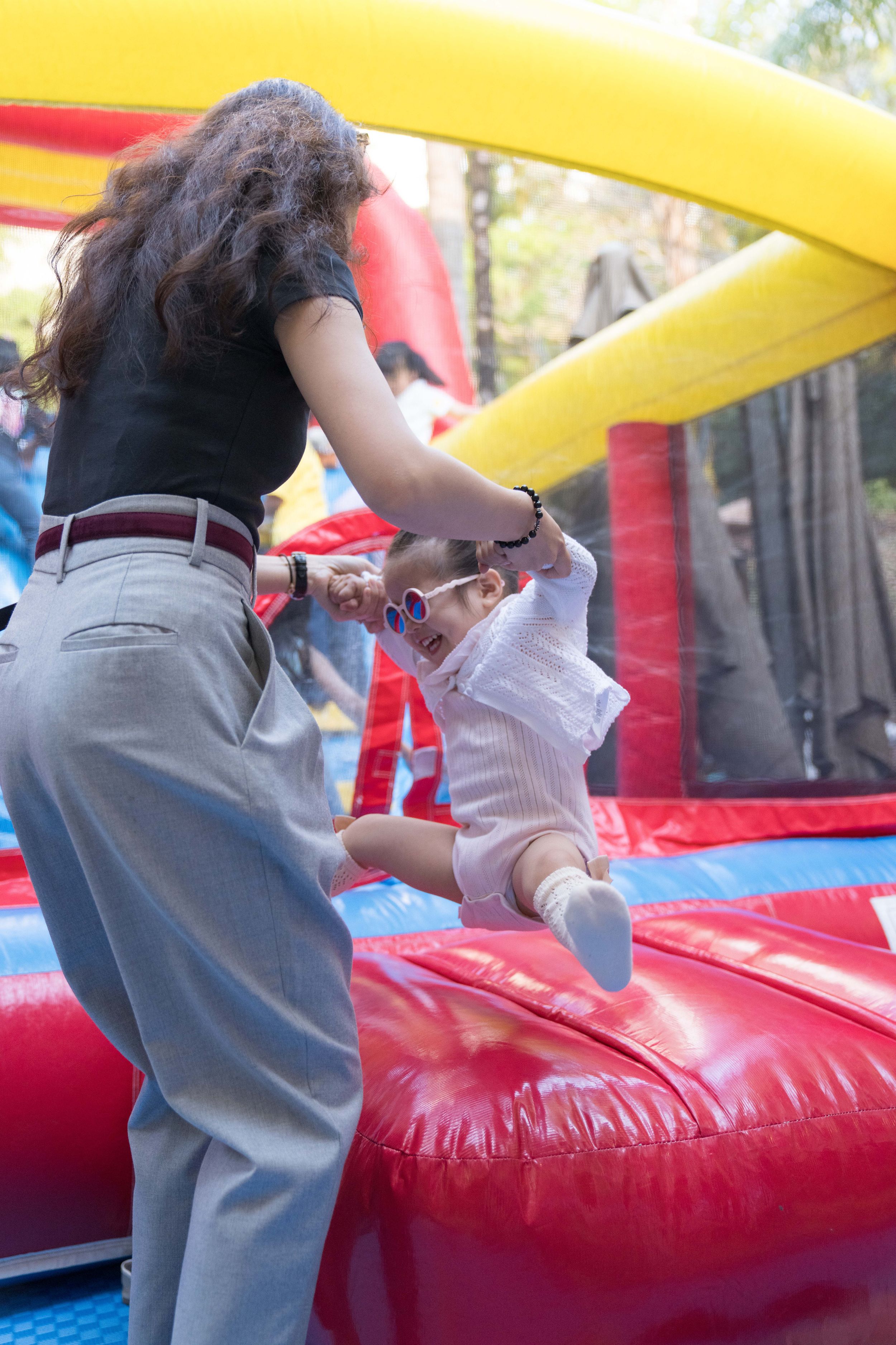 A sequence of photos shows a person attempting to climb over an inflatable red and yellow bounce house obstacle一組照片顯示，一名男子試圖爬過一個紅色和黃色的充氣彈跳床