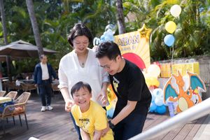 A joyful celebration at an outdoor birthday party with yellow balloons and decorations on a wooden deck.在木質平台上，人們舉行了一場歡樂的戶外生日派對，現場裝飾著黃色氣球