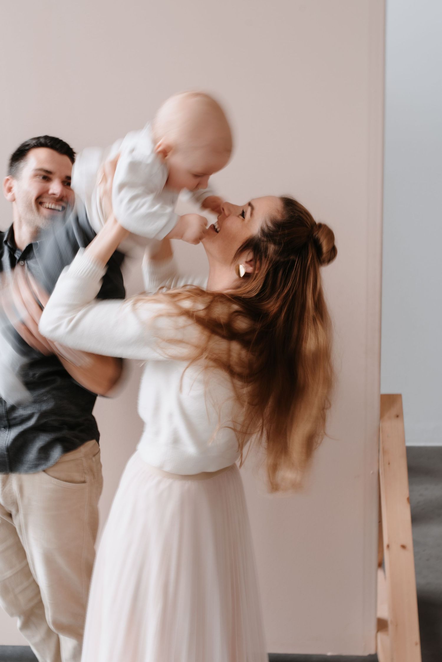 A couple dancing together in a romantic series of dips and poses against a light colored wall.
